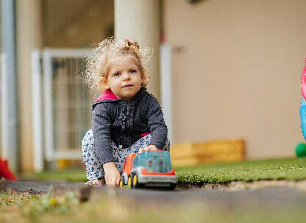 PHOTO D'UNE PETIT FILLE ENTRAIN DE JOUER AVEC UN CAMION
