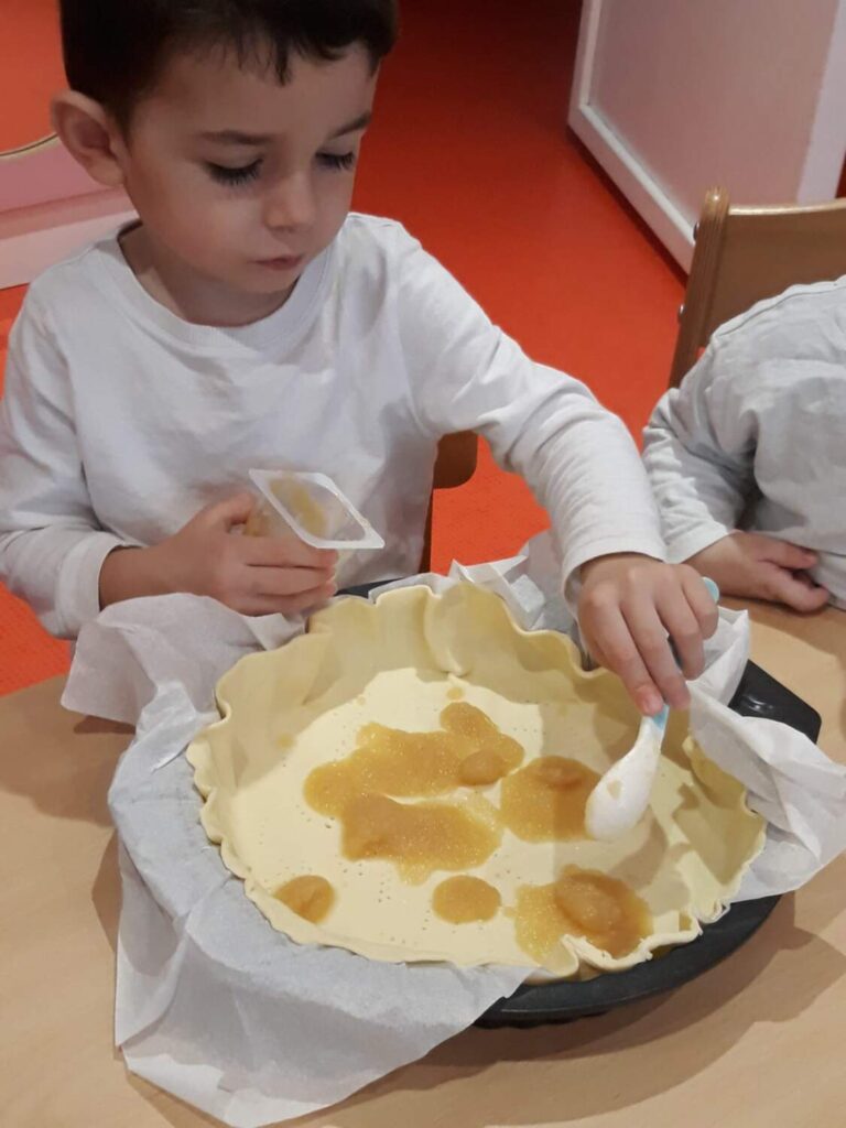 PHOTO DES ENFANTS DE LA CRÈCHE DES MINIS ENTRAIN DE PRÉPARER UNE GALETTE DES ROIS AVEC DE LA COMPOTE