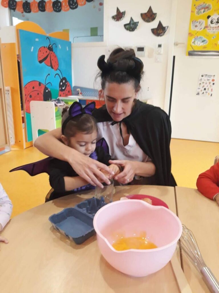 PHOTO D'UNE ÉDUCATRICE DE LA CRÈCHE DES MINSI ENTRAIN D'AIDER UNE FILLETTE À PRÉPARER UN GÂTEAU