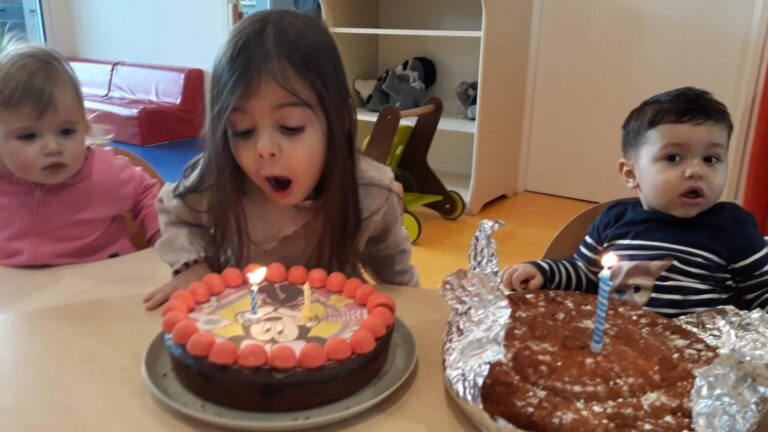 PHOTO D'UNE PETITE FILLE QUI SOUFFLE SES BOUGIES D'ANNIVERSAIRE À LA CRÈCHE DES MINIS