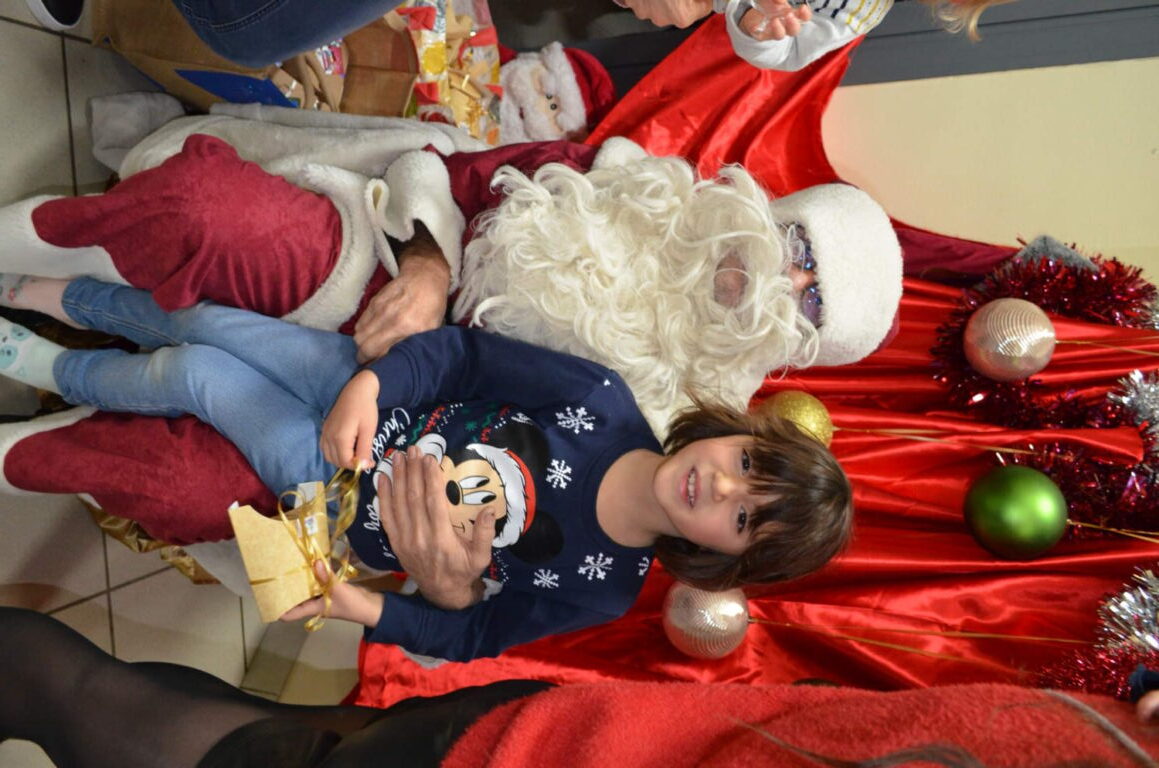 PHOTO D'UN MONSIEUR DÉGUISÉ EN PÈRE NOËL VEC UN ENFANT DE LA CRÈCHE DES MINIS