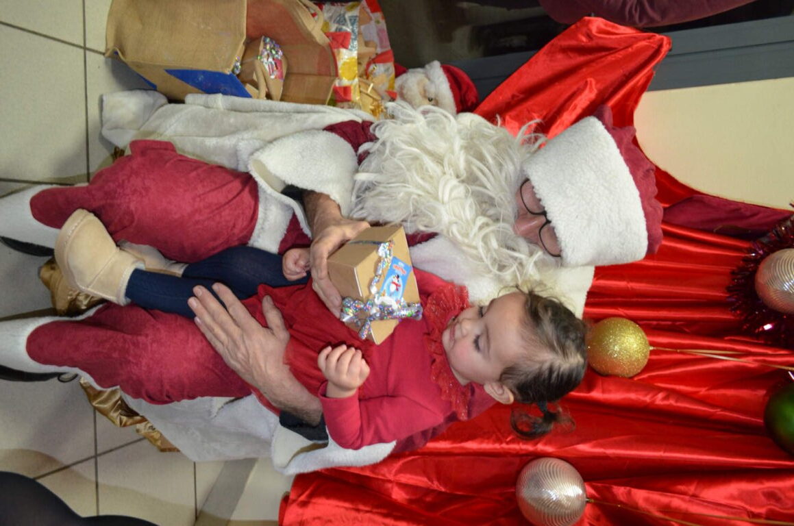 PHOTO D'UN MONSIEUR DÉGUISÉ EN PÈRE NOËL VEC UN ENFANT DE LA CRÈCHE DES MINIS