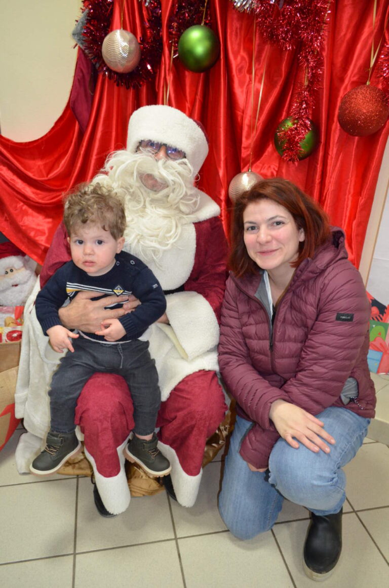 PHOTO D'UN MONSIEUR DÉGUISÉ EN PÈRE NOËL AVEC UN ENFANT ET SA MAMAN