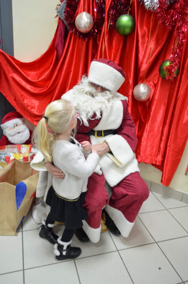 PHOTO D'UN MONSIEUR DÉGUISÉ EN PÈRE NOËL AVEC UNE PETITE FILLE DE LA CRÈCHE DES MINIS