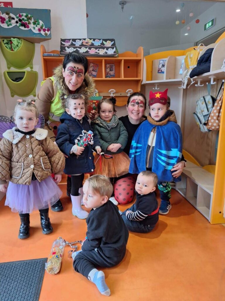 PHOTO D'UNE ÉDUCATRICE ET DES PETITS DE LA CRÈCHE DES MINIS DÉGUISÉS POUR LE CARNAVAL