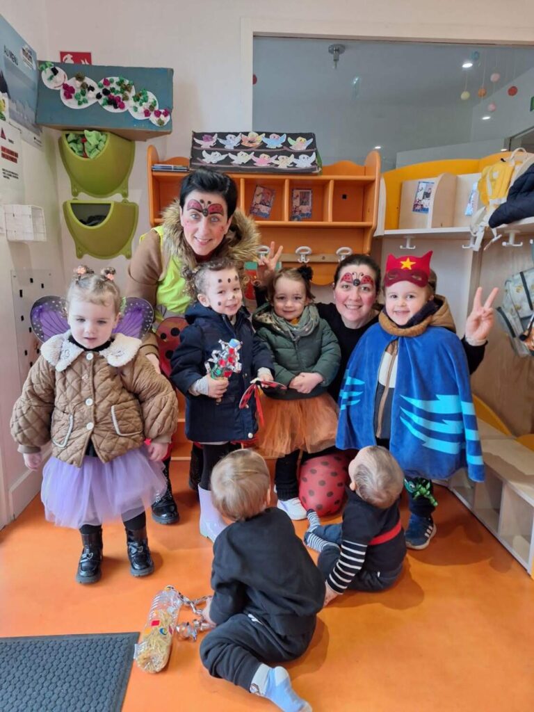PHOTO D'UNE ÉDUCATRICE ET DES PETITS DE LA CRÈCHE DES MINIS DÉGUISÉS POUR LE CARNAVAL