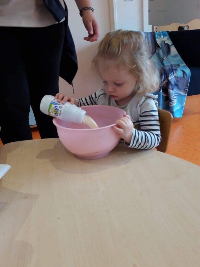 PHOTO D'UNE PETITE FILLE ENTRAIN DE VERSER DU LAIT DANS UN BOL