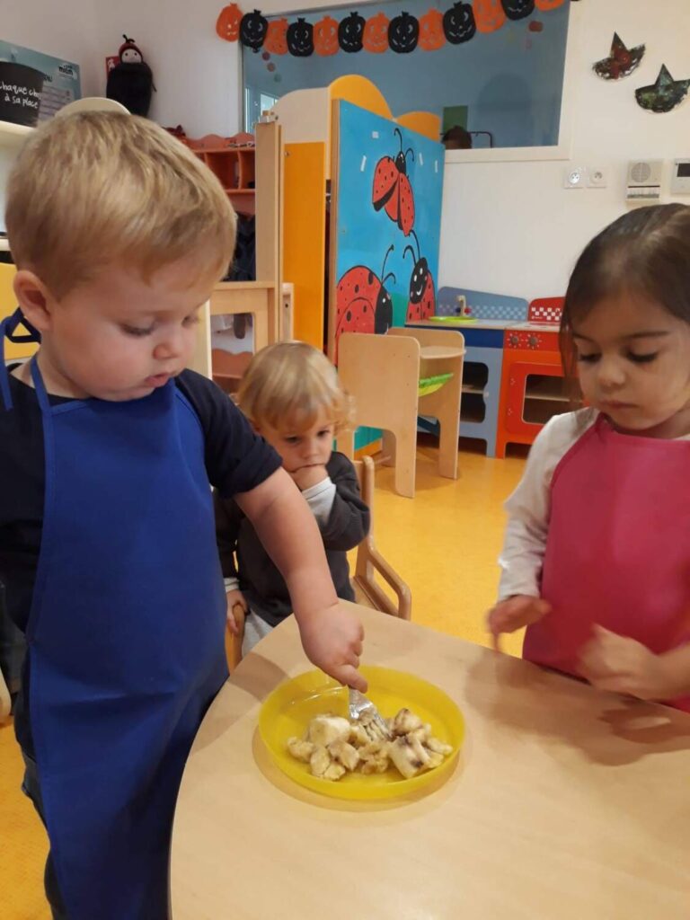 PHOTO D'UN PETIT GARÇON AVEC UN TABLIER ENTRAIN D'ÉCRASER DES BANANES