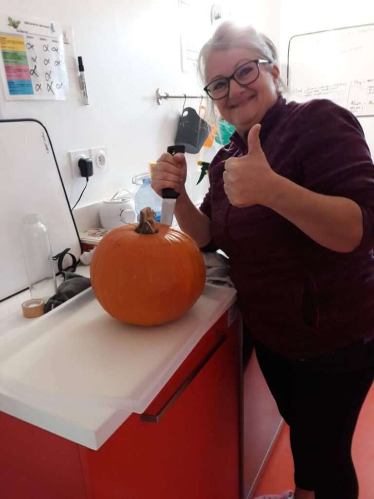 PHOTO D'UNE ÉDUCATRICE DE LA CRÈCHE DES MINIS QUI DÉCOUPE UNE CITROUILLE POUR HALLOWEEN