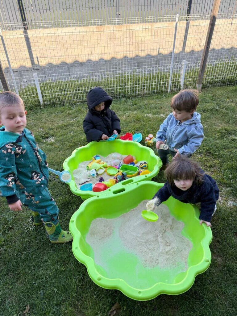 PHOTO DES PETITS ENFANTS DE LA CRÈCHE DES MINIS ENTRAIN DE JOUER DANS UN BAC À SABLE
