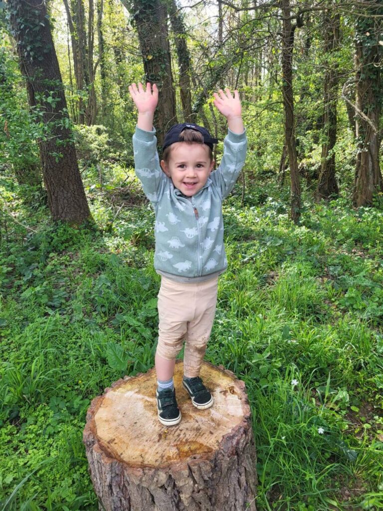 PHOTO D'UN PETIT GARÇON QUI SOURIT LES BRAS EN L'AIR