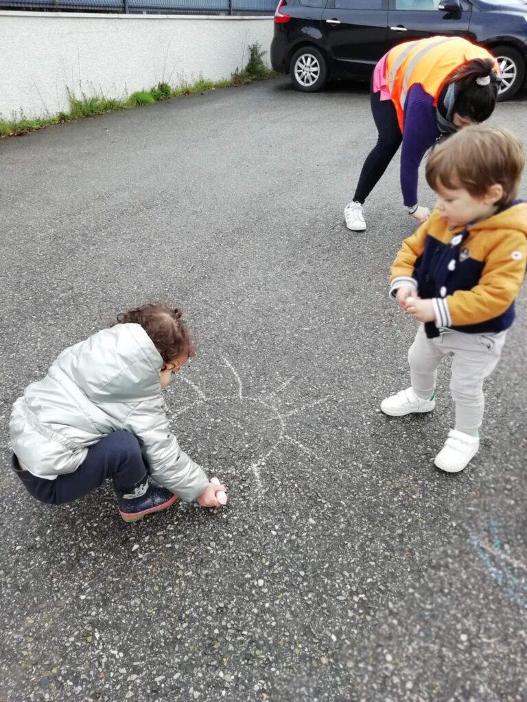 photo des enfants de la crèche des minis entrain de faire des dessins à la craie