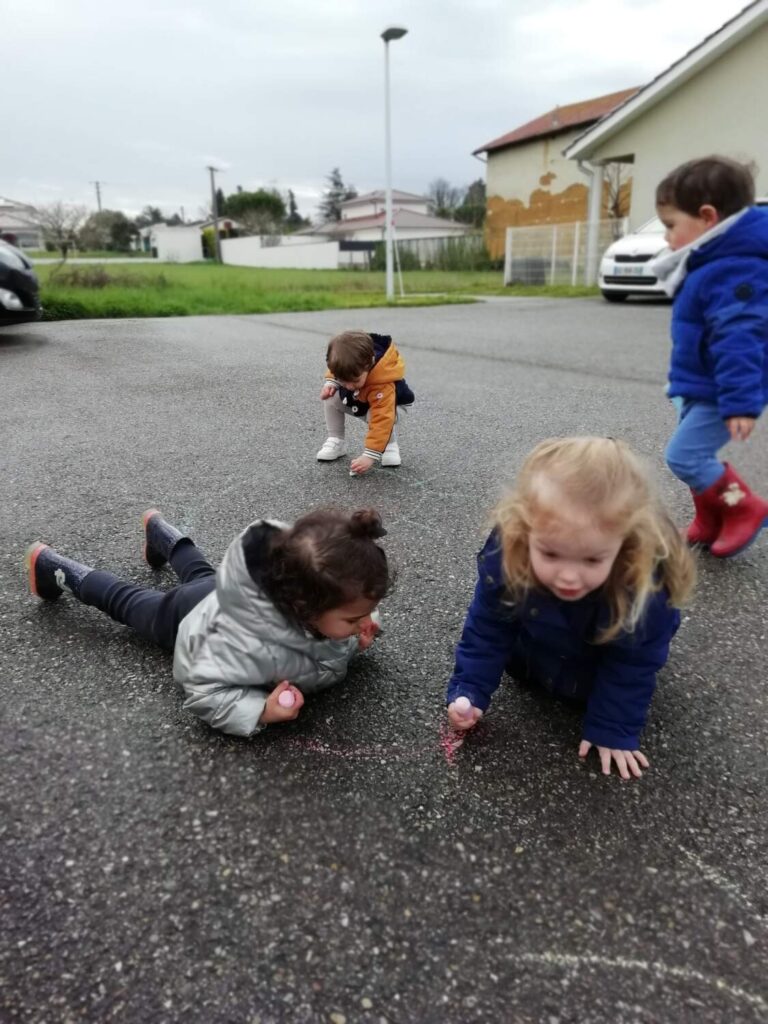 photo des enfants de la crèche des minis entrain de faire des dessins à la craie