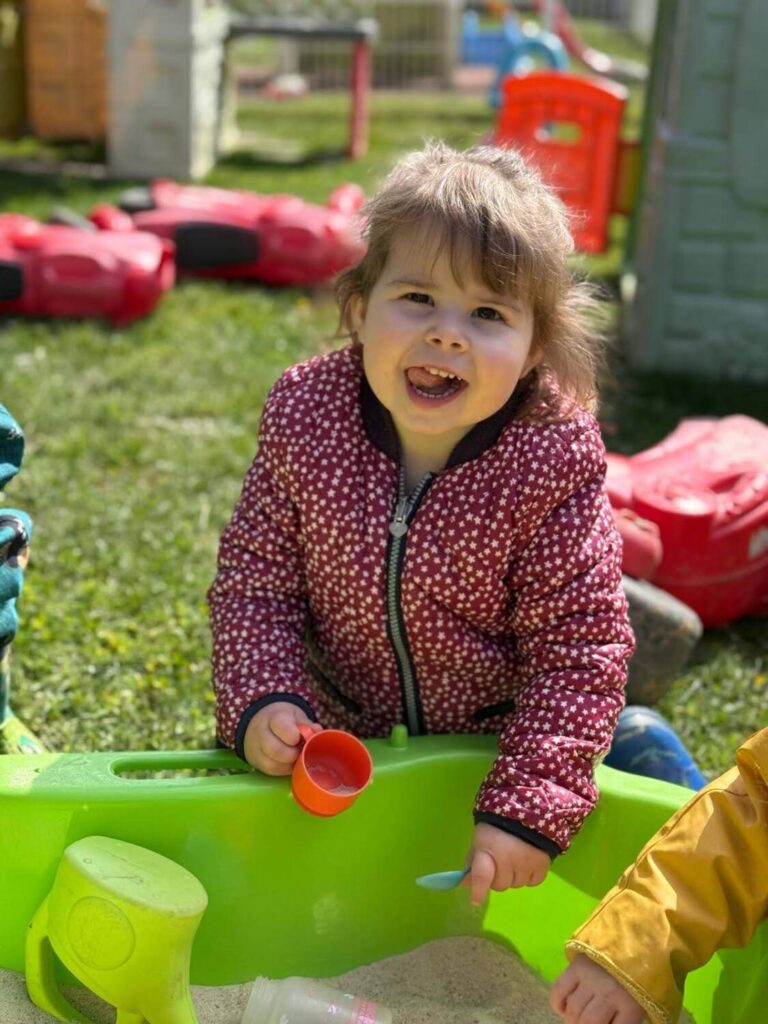 PHOTO D'UNE PETITE FILLE ENTRAIN DE JOUER DANS UN BAC À SABLE