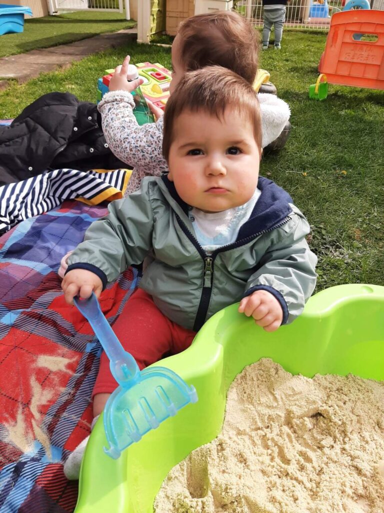 PHOTO D'UN PETIT GARÇON QUI JOUE DANS UN BAC À SABLE