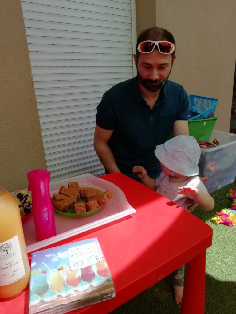 PHOTO D'UN PAPA AVEC SON BÉBÉ À UN GOÛTER ORGANISÉ PAR LA CRÈCHE DES MINIS
