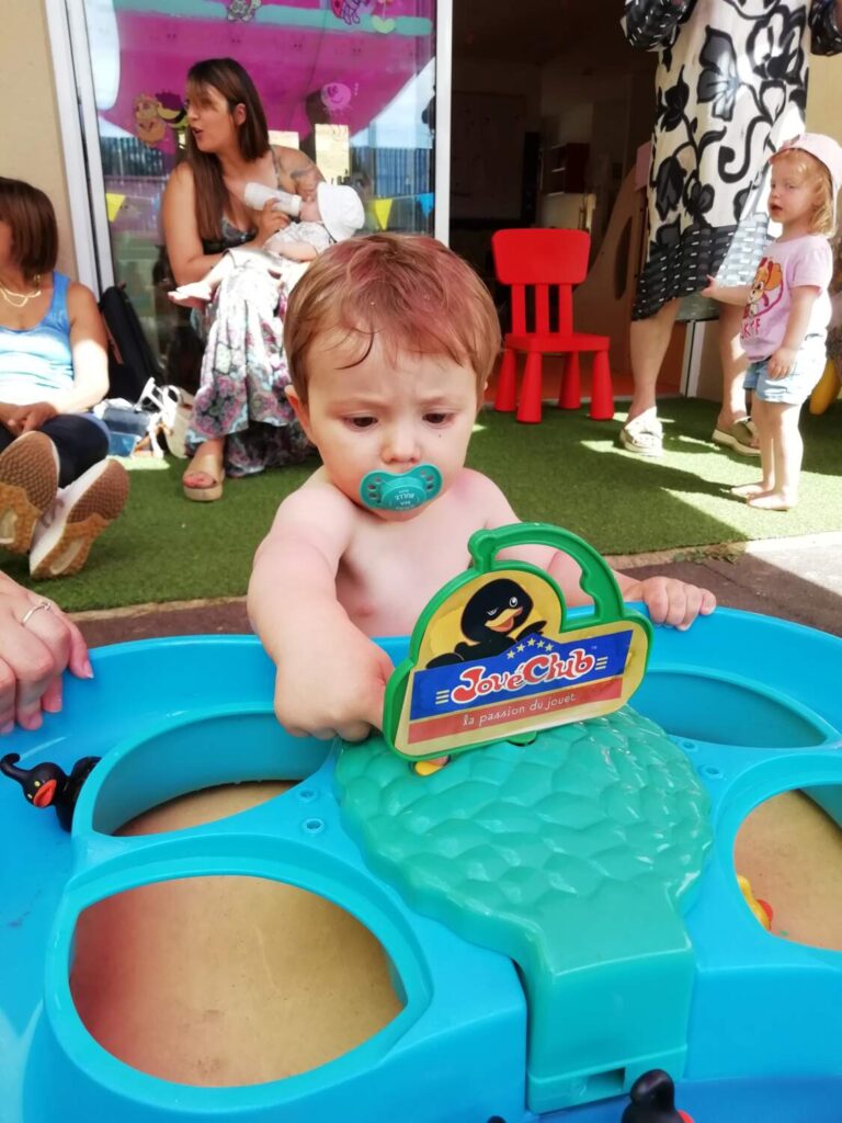 PHOTO D'UN PETIT GARÇON ENTRAIN DE JOUER AVEC UN JEU D'EAU