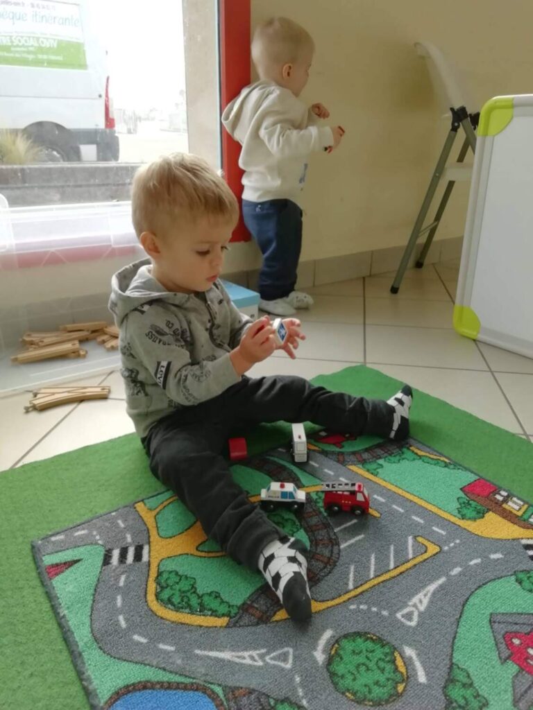 PHOTO D'UN PETIT GARÇON QUI JOUE AVEC DES PETITES VOITURES