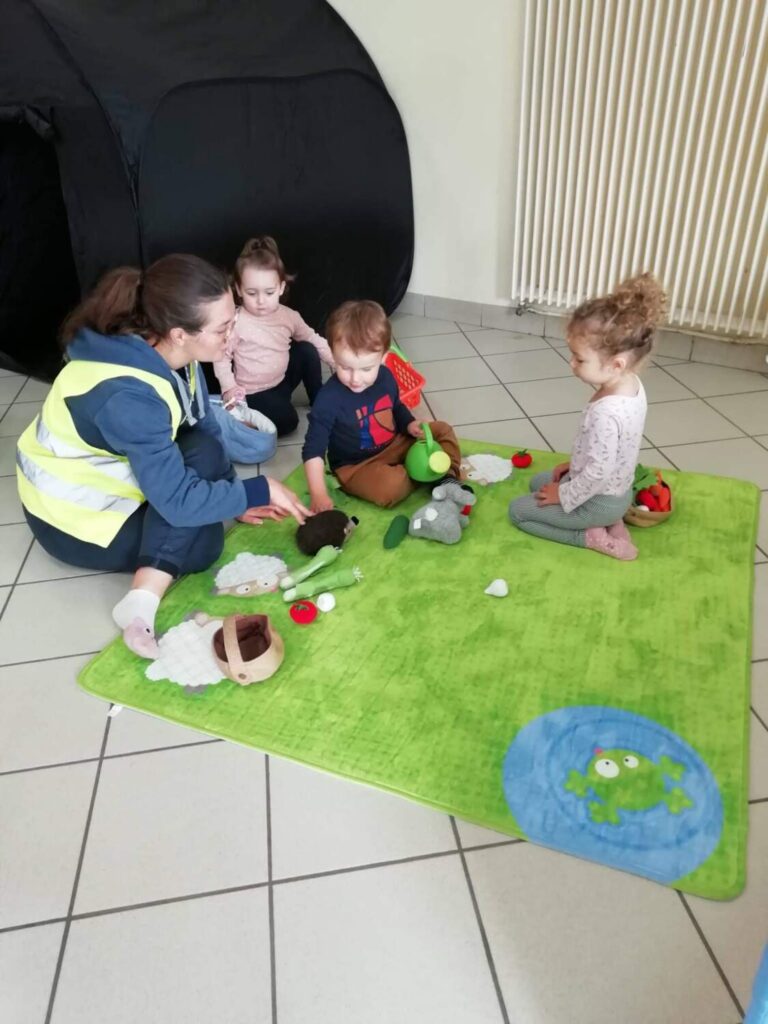 PHOTO D'UNE ÉDUCATRICE QUI JOUE AVEC LES ENFANTS DE LA CRÈCHE DES MINIS