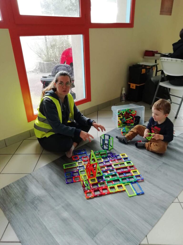 PHOTO D'UNE ÉDUCATRICE ENTRAIN DE JOUER AVEC UN PETIT GARÇON AVEC DES JEUX AIMANTÉS