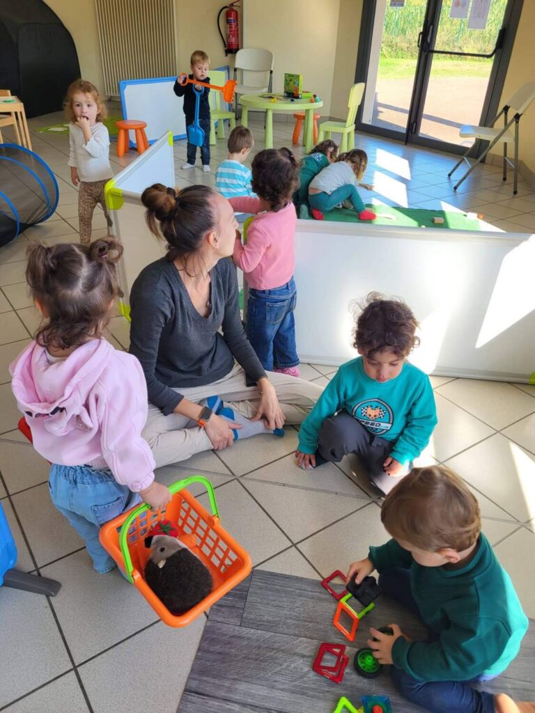 PHOTO D'UNE ÉDUCATRICE DE LA CRÈCHE DES MINIS ENTRAIN DE JOUER AVEC LES PETITS ENFANTS