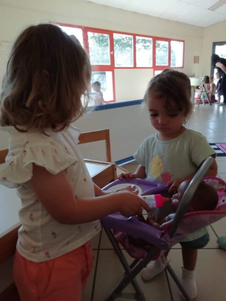 PHOTO DE DEUX PETITES FILLES ENTRAINE DE JOUER AVEC UN POUPON