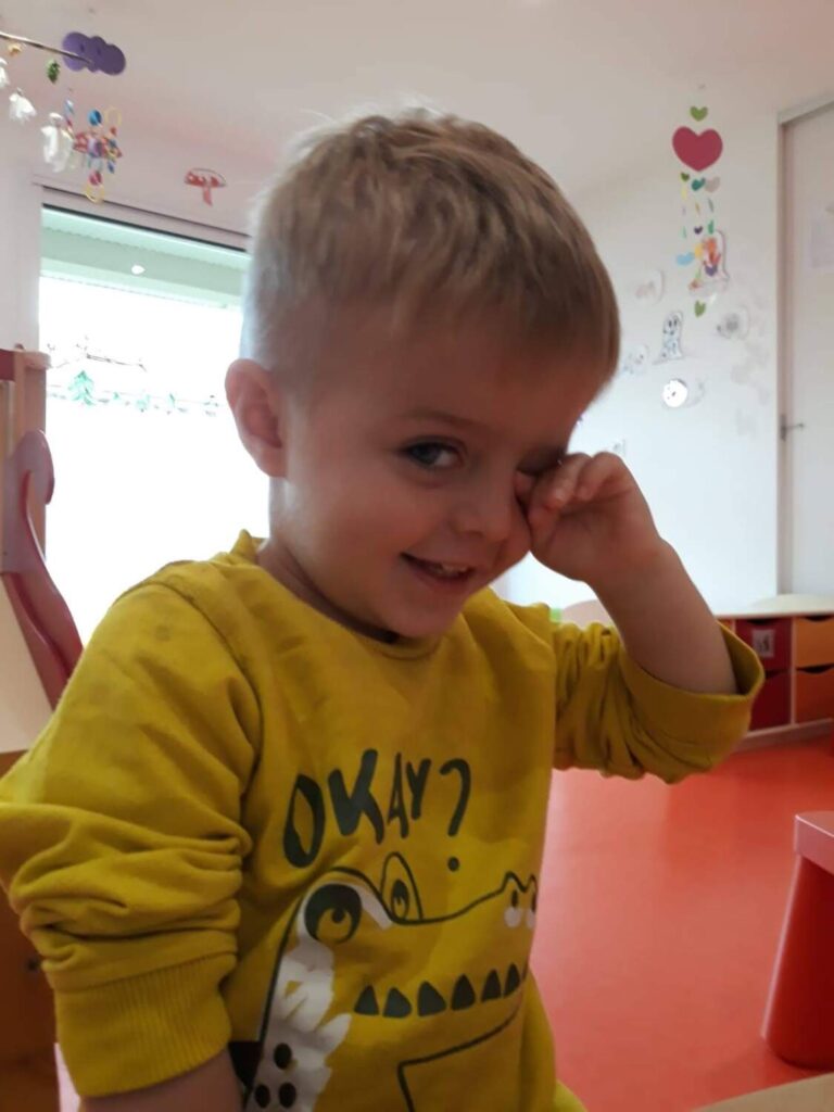 PHOTO D'UN PETIT GARÇON AVEC UN PULL JAUNE ENTRAIN DE SOURIRE